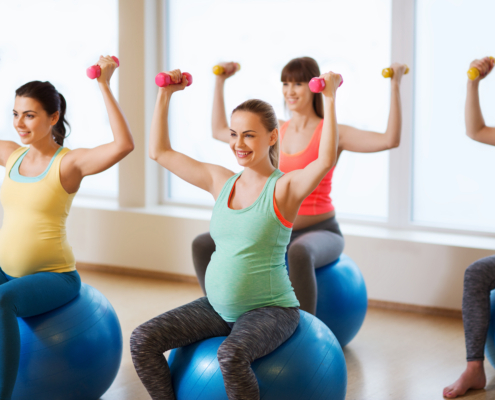 happy pregnant women exercising on fitball in gym
